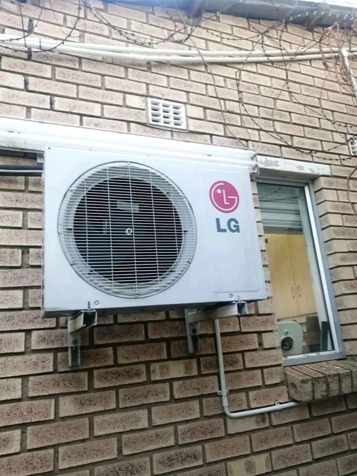 Air conditioning condenser secured to an exterior brick wall