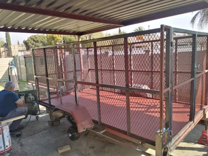 Steel mesh cage trailer during fabrication under a carport