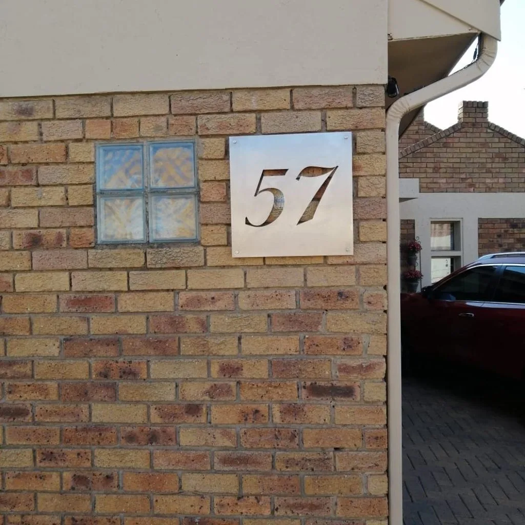 Custom house number 57 plaque mounted on a brick wall