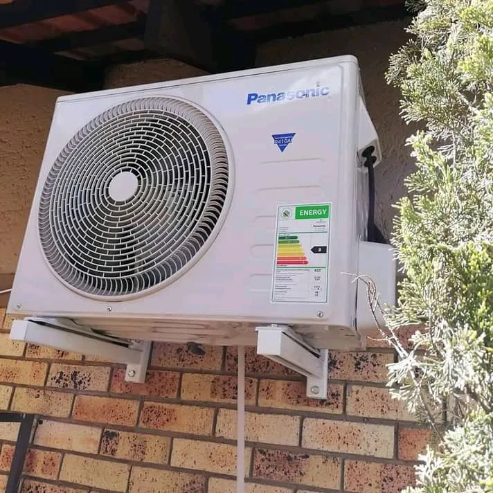 Outdoor air conditioning condenser mounted on a brick wall