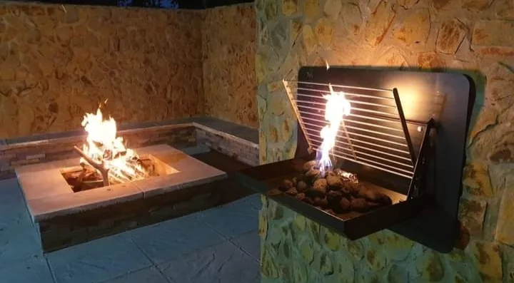 Wall-mounted fold-down braai with flames and cooking grates