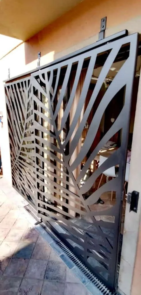 Steel driveway gate with decorative leaf-pattern panels