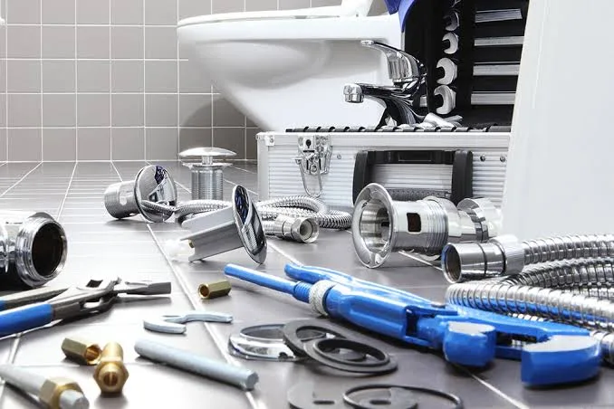 Plumbing tools and pipe fittings beside a bathroom basin