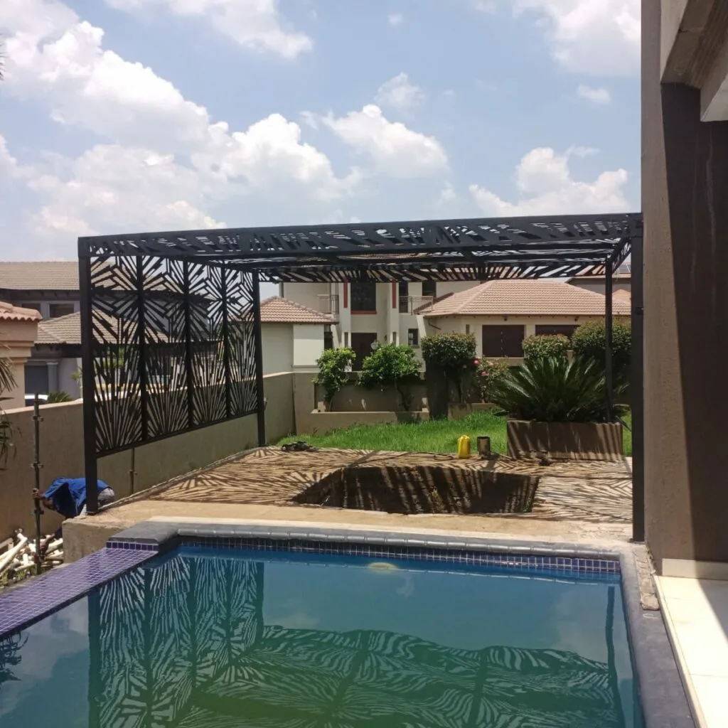 Decorative steel pergola roof beside a residential patio