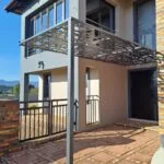 Steel balcony railing and entrance pergola at a two-storey home