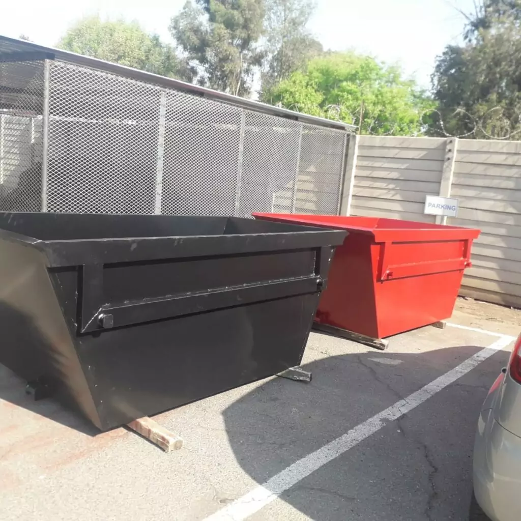 Black and red steel skip bins in a fabrication yard