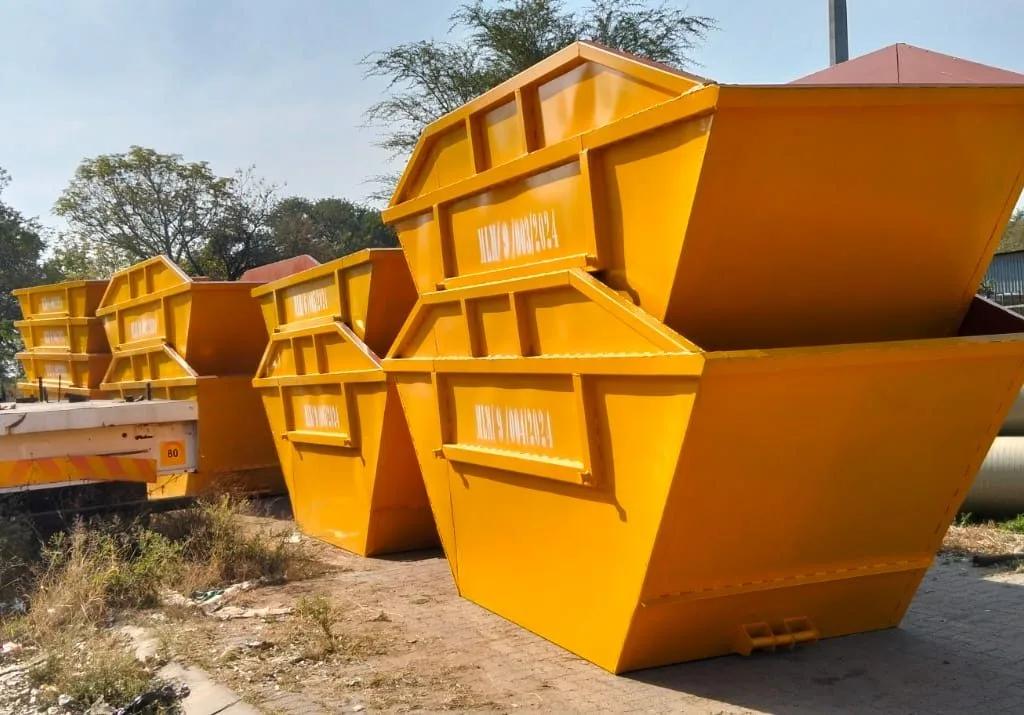 Orange steel skip bins for sale stacked in a manufacturing yard