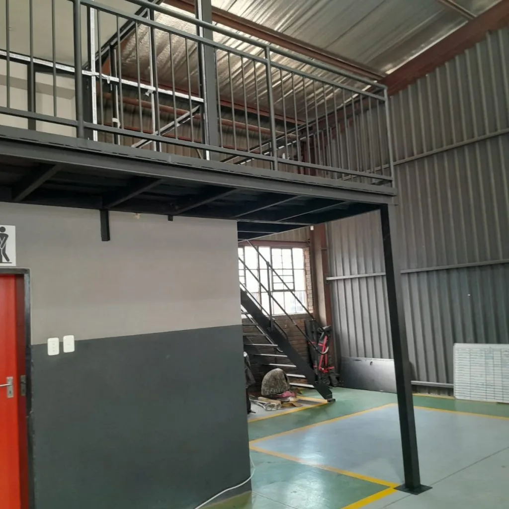 Steel mezzanine floor above warehouse rooms and a red door