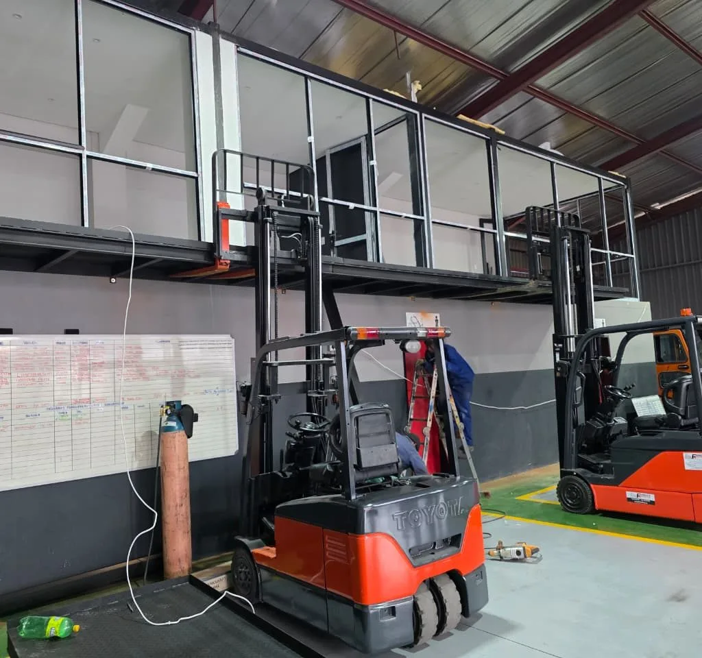 Steel mezzanine offices and balcony railings above warehouse space